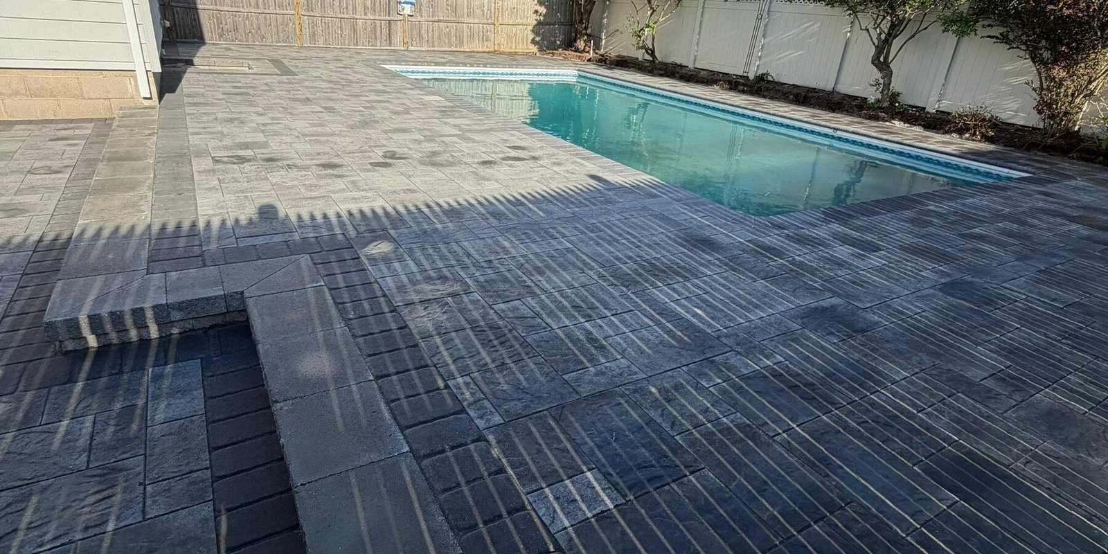 Paver pool deck at dusk with the water lit from inside