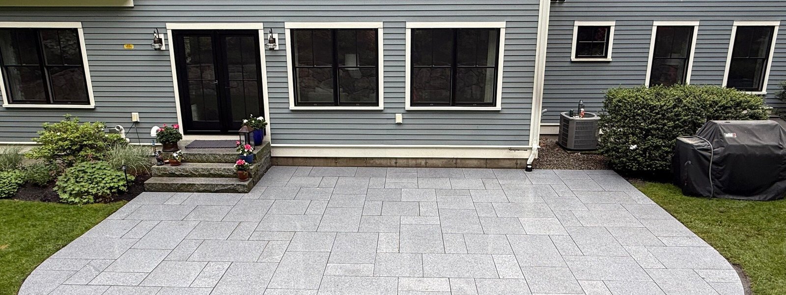 Light granite paver patio behind a home