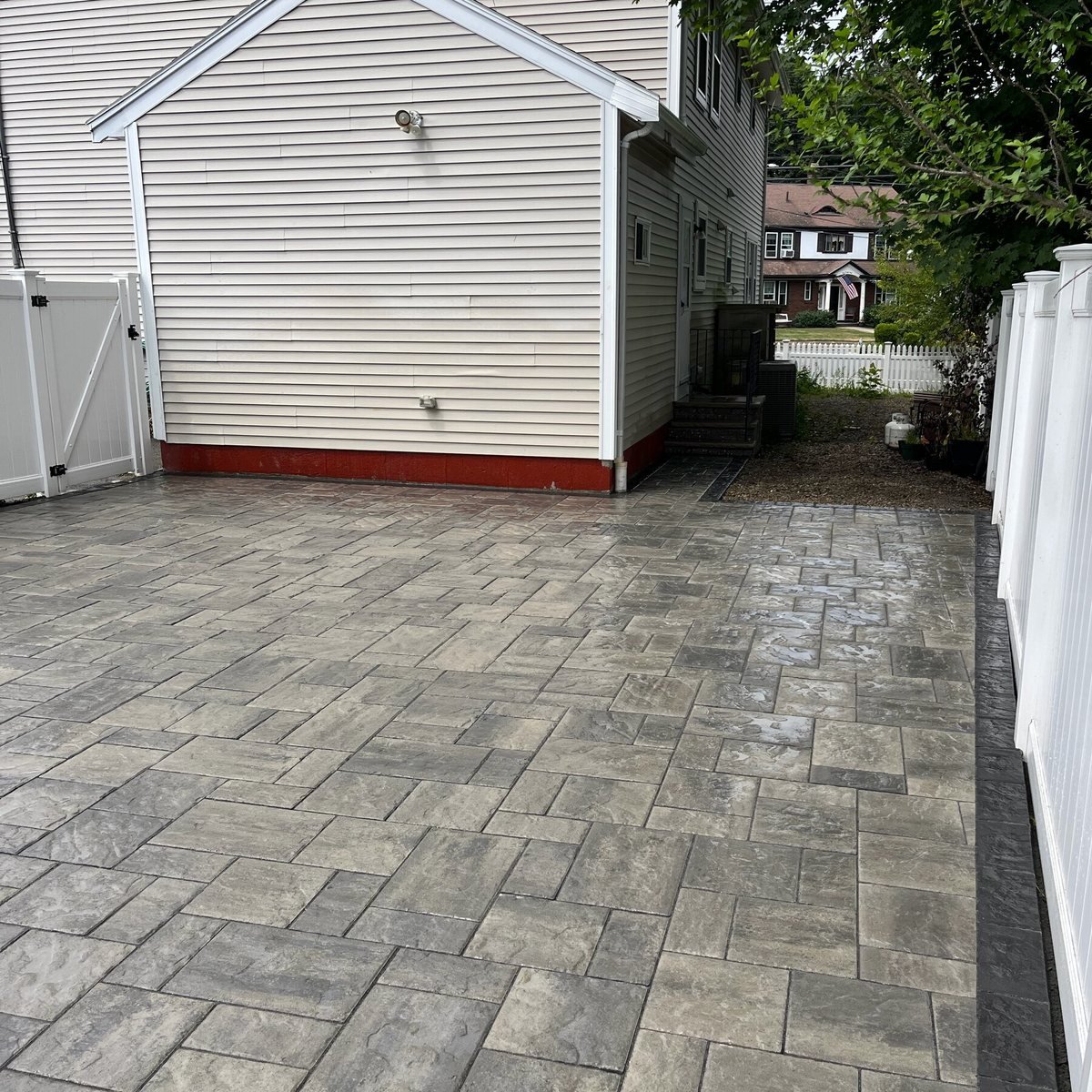 Paver driveway running along the side of a white house